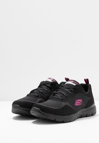 Scarpe da ginnastica nere con tomaia in rete, logo e dettagli rosa, design con lacci, collo imbottito e suola testurizzata per una buona aderenza.