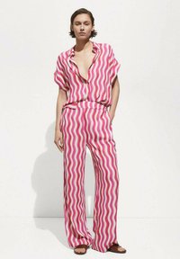Pink and white striped two-piece outfit with a loose-fitting short-sleeve shirt and wide-leg pants, featuring wave patterns and a relaxed design.