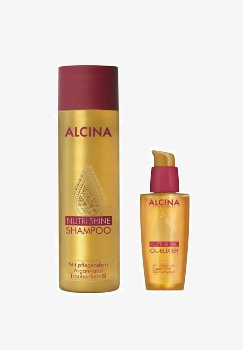 Gold shampoo bottle and smaller oil elixir, both with maroon caps. Labels in contrasting colors, featuring decorative designs and product names.