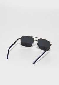 Gafas de sol cuadradas con lentes oscuros, armazón metálico y patillas azul marino. Incluyen almohadillas nasales de silicona para mayor comodidad y agarre.