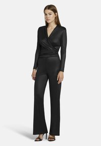 Zwart jumpsuit met een wikkelstijl top en lange mouwen, met een aansluitende taille en brede broekspijpen. Soepele, matte textuur.