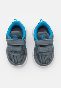 Para szarych i niebieskich sneakersów Adidas dla małych dzieci z rzepami widziana z góry na białym tle.