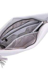 Interno di una borsa in pelle bianca perforata con una fodera grigia. Presenta una tasca con zip e una tasca a soffietto, entrambe in tessuto liscio con dettagli del logo.