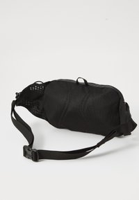 Schwarze Stofftasche mit abgerundeter Form, verstellbarem Tragegurt, Reißverschlussverschluss und Netzdetails auf einer Seite. Leichtes und kompaktes Design.