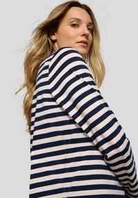 Striped long-sleeve top in navy and cream fabric, featuring a relaxed fit with a round neckline and soft texture. Visible seam details.