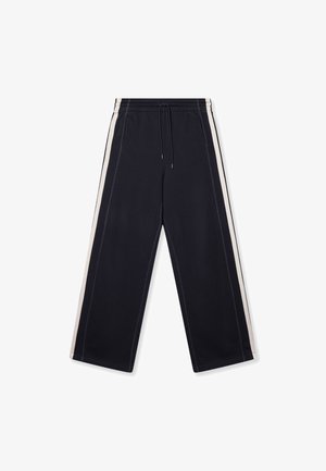Schwarze, weit geschnittene Hose mit strukturierter Oberfläche, versehen mit weißen Seitestreifen, elastischem Bund mit Kordelzug und zwei vorderen Taschen.
