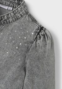Chemise en denim gris avec col, manches bouffantes et ornements en strass à l'avant pour plus de détail.