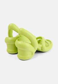 Vihreät kumisaappaat, joissa on ainutlaatuinen hihnadesign ja pyöristetyt, muotoillut pohjat mukavuutta ja tukea varten. Keskikohdan teksturoitu pohja antaa paremman pidon.