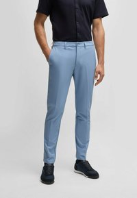 Light blue tailored pants made from a smooth, stretchy fabric. The design features side pockets and a classic zip fly with button closure.