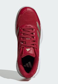 Rød sportssko med mesh-overdel og syntetiske detaljer, med snørelukning, hvid sål og logodetaljer på tungen og indersålen.