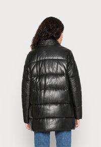 Černá kožená péřová bunda s vysokým límcem, prošívaným designem a volným střihem. Textura je hladká s polstrovanými částmi.