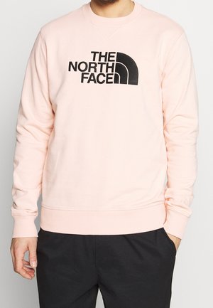 Sweatshirt rose clair en mélange de coton, avec un logo noir imprimé sur la poitrine. Manches et ourlet côtelés. Coupe régulière.