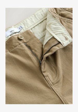Khaki chinos med en knap- og lynlåslukning, der har en blød stoftekstur og en indvendig taljebåndsforing i lys beige.