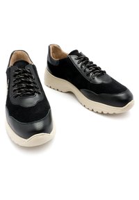 Czarne zamszowe i skórzane sneakersy z masywną beżową gumową podeszwą oraz czarnymi sznurowadłami. Zawierają akcenty w postaci przeszyć i okrągły kształt noska.