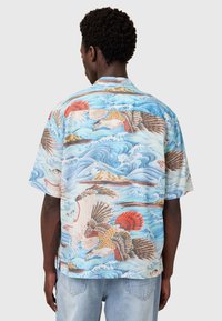 Kurzärmliges Hemd aus lebendig blauer Stoff mit von Japan inspirierten Mustern von Vögeln und Wellen, akzentuiert mit roten und braunen Highlights.