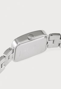 Silver metal watch with a rectangular case, textured crown, and linked bracelet. Smooth finish with clear back and metallic accents.