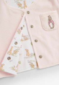 Cardigan rosa chiaro con una texture morbida, dotato di bottoni a pressione e una tasca con un coniglio ricamato. Foderato all'interno con un tessuto a motivo conigli.