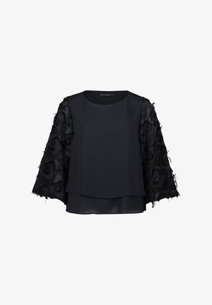 Black top with a solid front and layered back. Sheer, frayed fabric sleeves with textured floral patterns. Round neckline, loose fit.