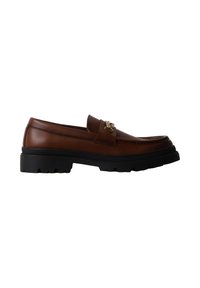 Mocassin en cuir marron avec semelle épaisse noire et détail en métal doré sur le dessus, vu de côté sur fond blanc.