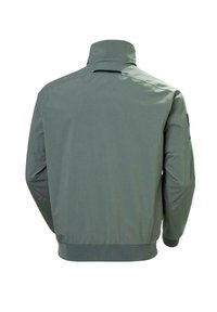 Chaqueta verde, ligera, con un collar alto, dobladillo y puños acanalados, que presenta una textura suave y un diseño minimalista.