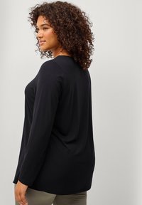 Sort langærmet top lavet af blødt stof, med en afslappet pasform og rund halsudskæring, med en glat tekstur og et minimalistisk design.