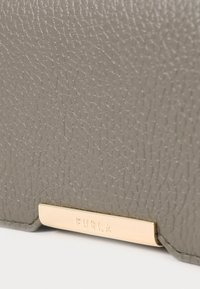 Geldbörse aus grauem strukturiertem Leder mit einem Akzent aus goldenem Metall. Ausgestattet mit dem geprägten Markennamen "Furla" auf einer polierten Metallplatte.
