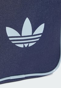 Borsa blu navy con un logo Adidas azzurro chiaro caratterizzato da tre forme a foglia e tre strisce. Materiale in tessuto texturizzato con rifinitura liscia.