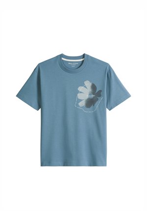 Blauw T-shirt met korte mouwen en ronde hals, met een grote lichtgrijze en donkergroene bloemafbeelding en witte cirkeltekst op de linkerborst.