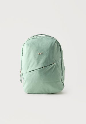 Nike nahrbtnik v barvi mete z majhnim diagonalnim žepom z zadrgo spredaj in zgornjim ročajem za prenašanje na enobarvni svetli podlagi.