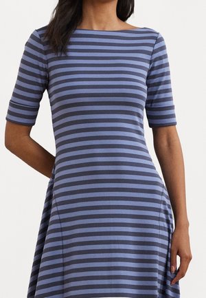 Nainen, jolla on siniharmaaraidallinen mekko, jossa on kyynärpään mittaiset hihat ja venekaulus.