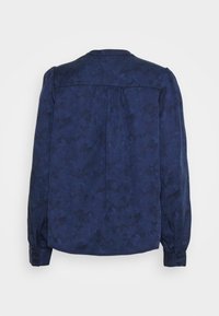 Blusa blu navy con motivo floreale strutturato, dotata di scollatura rotonda, maniche lunghe e polsini con bottone. Il retro presenta un dettaglio con balza.