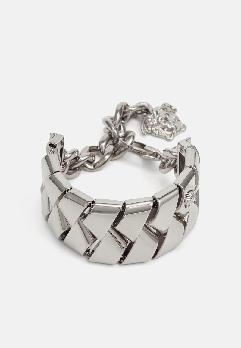 Metallarmband med en kraftig, sammankopplad design. Har en polerad silverfinish, länkar och ett dekorativt spänne med en lejonhuvuddetalj.