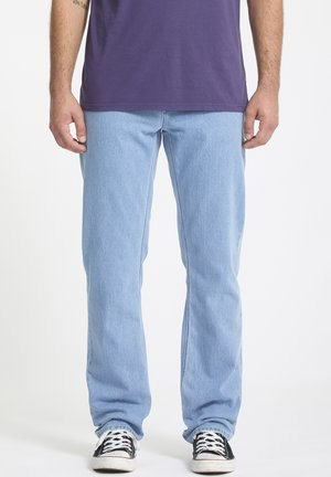 Light blue straight-leg jeans made of denim, featuring a classic five-pocket design and worn with black and white sneakers.