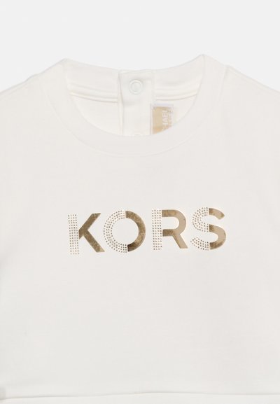 Λευκό ένδυμα με μεταλλικό χρυσό κείμενο "KORS" μπροστά και δύο κουμπιά με πατ απο το γιακά.