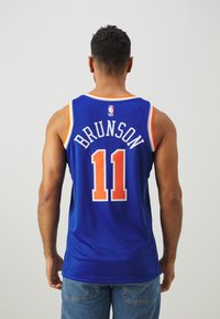 Blå basketballtrøje med orange detaljer, spillernavn "BRUNSON" og nummer "11" på bagsiden, med mesh-struktur og uden ærmer.