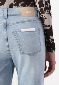 Ljusblå denimjeans med en beige läderlapp märkt "JJXX" på baksidan. Har en liten vit etikett i bakfickan.