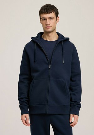 Granatowy rozpinany sweatshirt wykonany z tkaniny z bawełną. Posiada kaptur ze sznurkiem, przednie kieszenie oraz ściągacze na mankietach. Prosty, nowoczesny design.