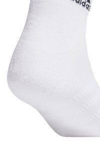 White sock made of textured material with a ribbed cuff. Features a black patterned accent at the top edge, smooth throughout the body.