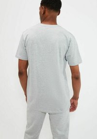 Camiseta de manga corta gris con escote redondeado, hecha de una tela suave, con un corte relajado y un dobladillo recto.