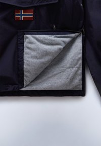 Chaqueta navy con parche de la bandera noruega, con un bolsillo interior forrado de gris y suave al tacto, que presenta una textura suave y cremalleras lisas.