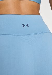 Világoskék leggings sima textúrával, sötét logóval a derekánál és varrás nélküli dizájnnal.