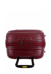 Valise rigide maroon avec une fermeture éclair, serrure à combinaison TSA et une poignée télescopique noire déployée.