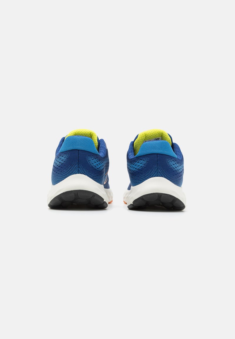 Zapatillas deportivas azules con parte superior de malla, cuello acolchado y acentos interiores en un brillante color amarillo. Media suela blanca y suela exterior texturizada en negro.