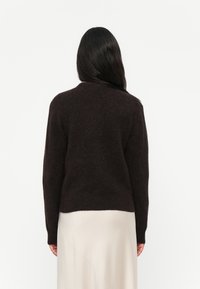 Maglione in lana marrone scuro con maniche lunghe e scollatura a girocollo, caratterizzato da una vestibilità comoda e una texture morbida, mostrato da dietro.