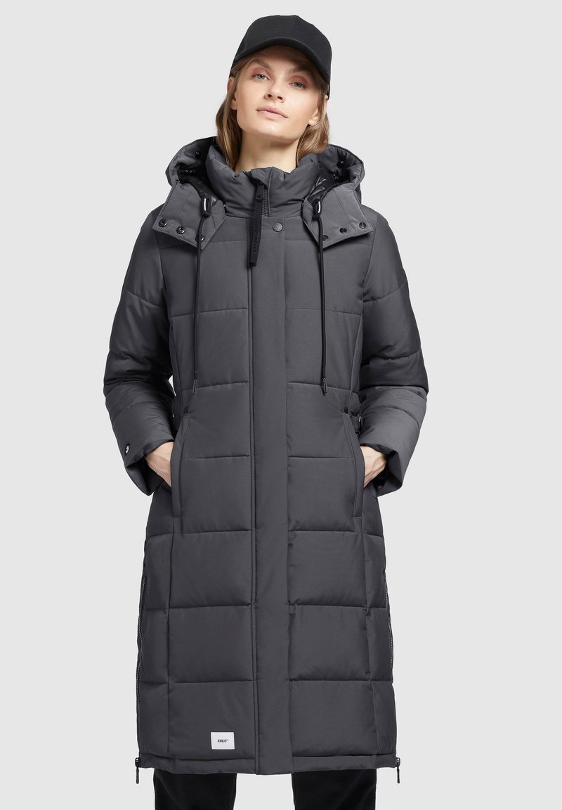 Grauer langer Daunenmantel mit Kapuze, vertikalen Steppnähte, Kordelzügen, seitlichen Taschen und einem Logotag nah am Saum.