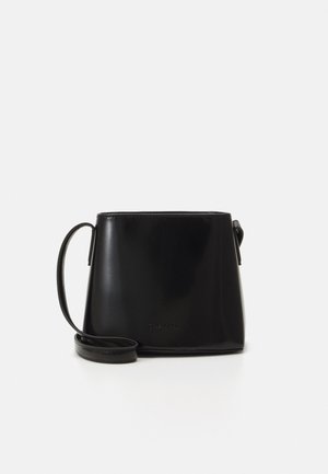 Zwarte emmerzak van glanzend leer met een eenvoudige, gestructureerde vorm. Beschikt over een dunne, verstelbare strap en een reliëflogo detail aan de voorkant.