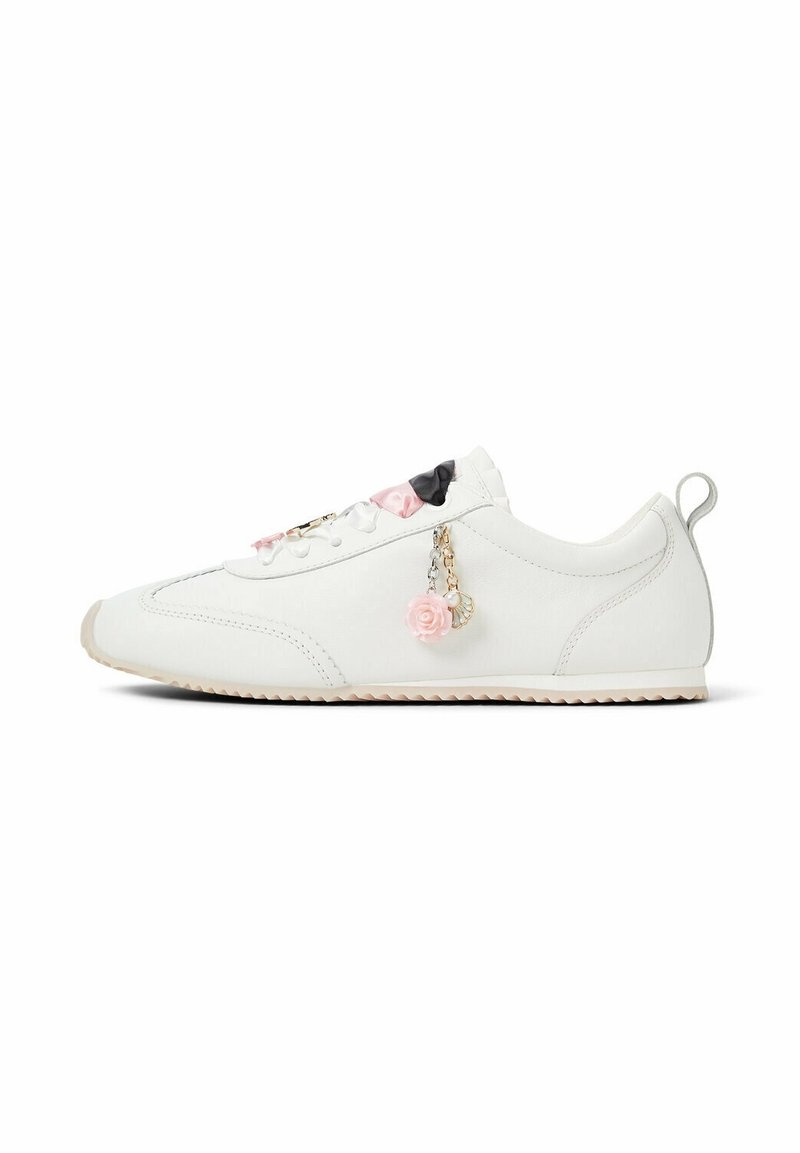 Baskets basses blanches avec semelle en caoutchouc, accents rose et noir sur la languette, et un pendentif rose en forme de rose suspendu aux lacets.