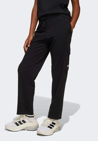 Svarta joggingsbyxor i mjukt material, med elastisk midja och dragsko, sidofickor och cargoficksdetalj.