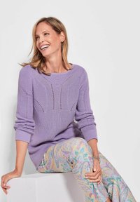 Lila gestrickter Pullover mit strukturiertem Design und Rundhalsausschnitt, kombiniert mit pastellfarbenen Paisleymuster-Hosen in hellblauen und rosa Farbtönen.