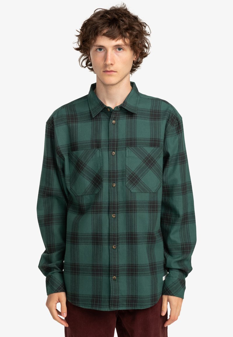 Grønternet flannel skjorte med to brystsække, knaplukning og krave. Har mørke ternede mønstre og en blød tekstur.